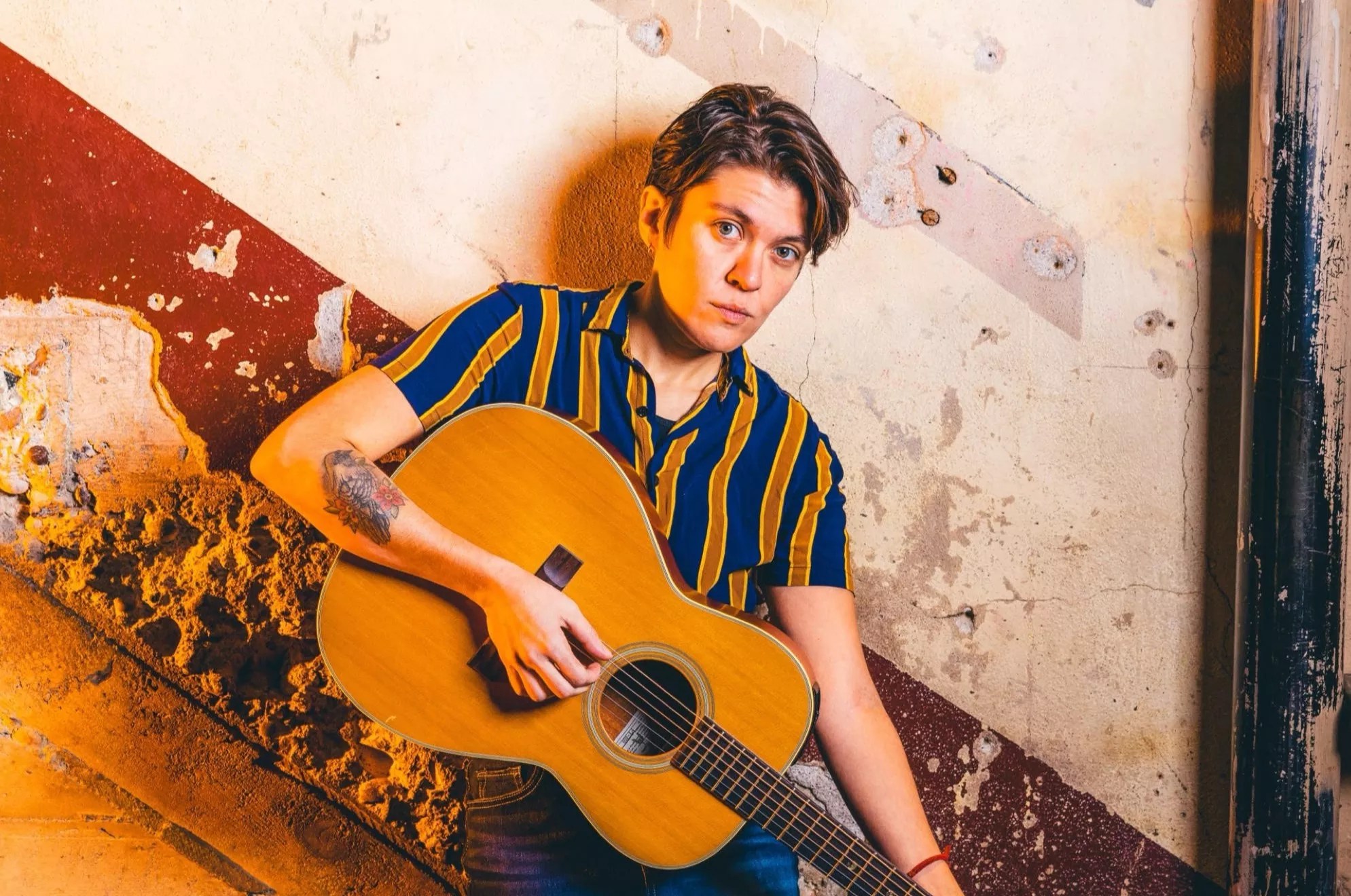 A woman with short hair holding a guitar.