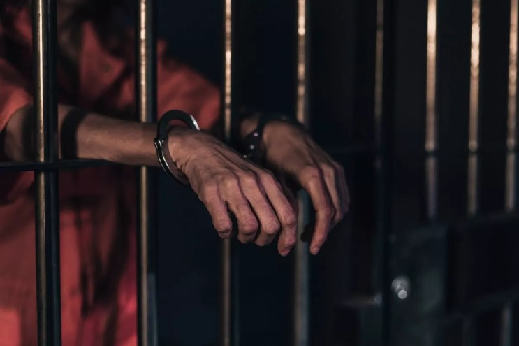 Handcuffed hands stick outside prison bars