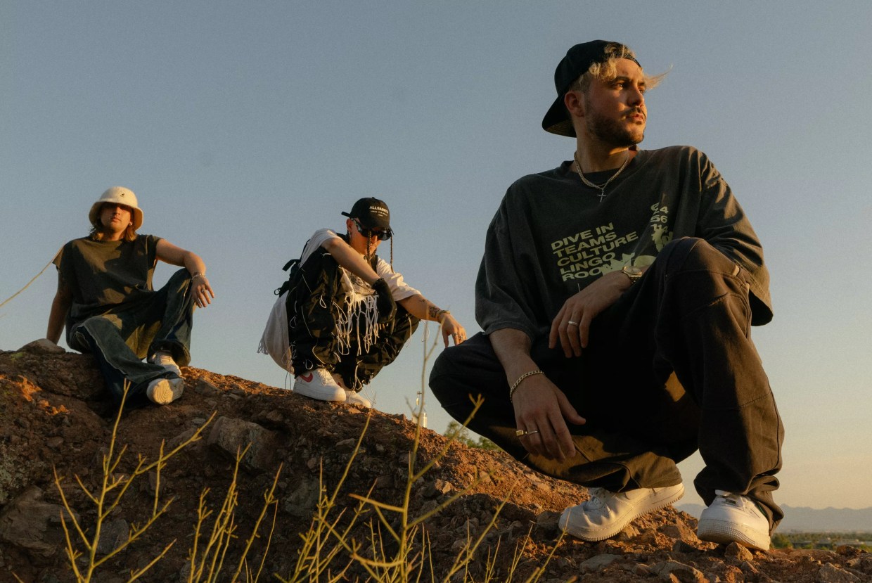 Three young men posing on a hill.