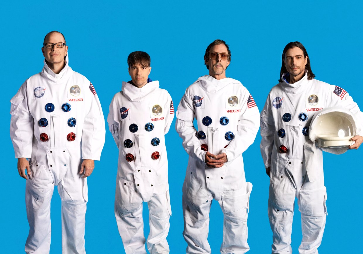 Four men in space suits in front of a blue background.