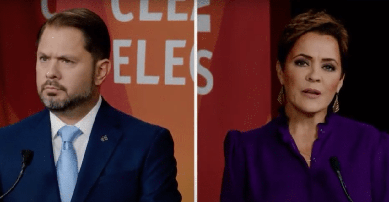 ruben gallego wears an incredulous facial expression while kari lake speaks to a camera
