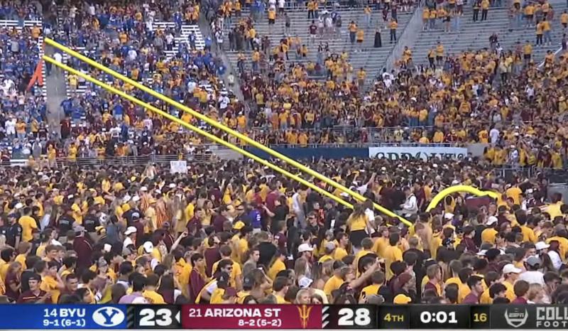 a screenshot of a football game showing fans toppling the goalpost with one second still on the game clock