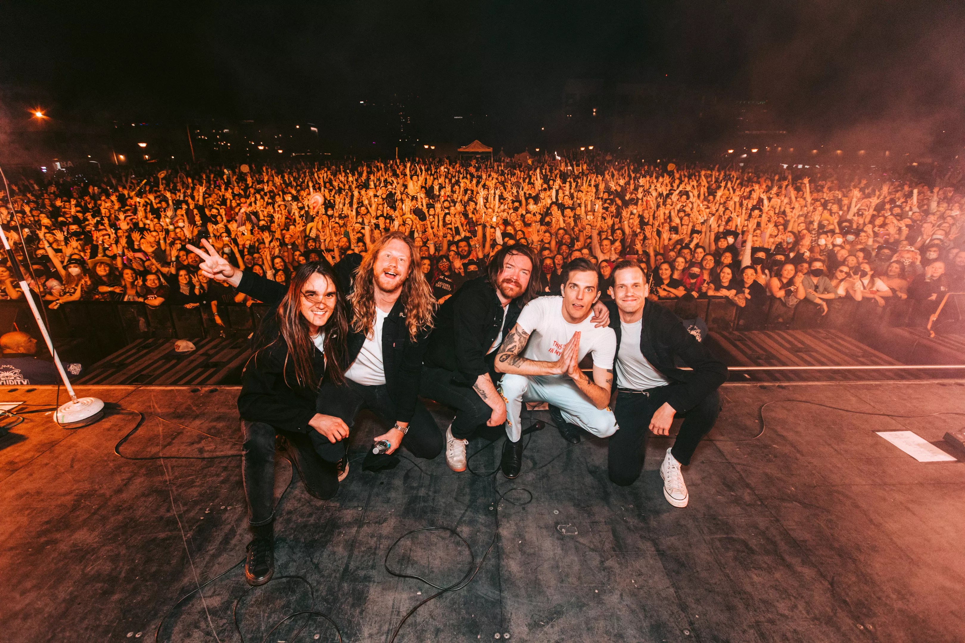 Band crouches on stage in front of crowd.