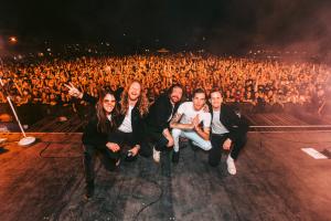Band crouches on stage in front of crowd.