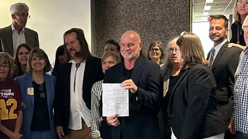 a man holds up a sheet of paper surrounded by other people