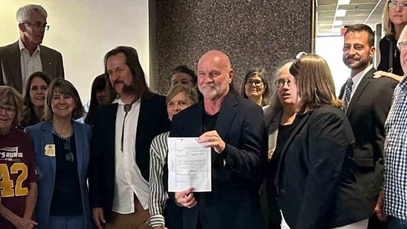 a man holds up a sheet of paper surrounded by other people