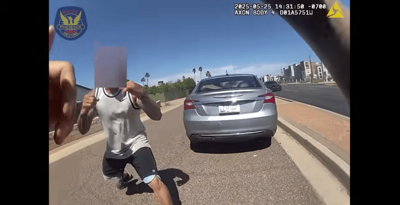 body-camera footage showing a man with a sleeveless shirt and tattoos down his arms squaring up to fight