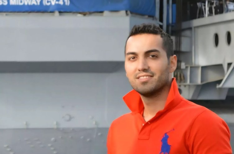 a man in an orange polo shirt with the collar flipped up