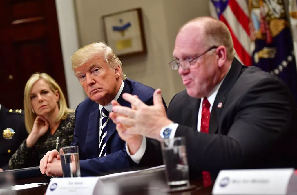 tom homan sits next to donald trump at a table