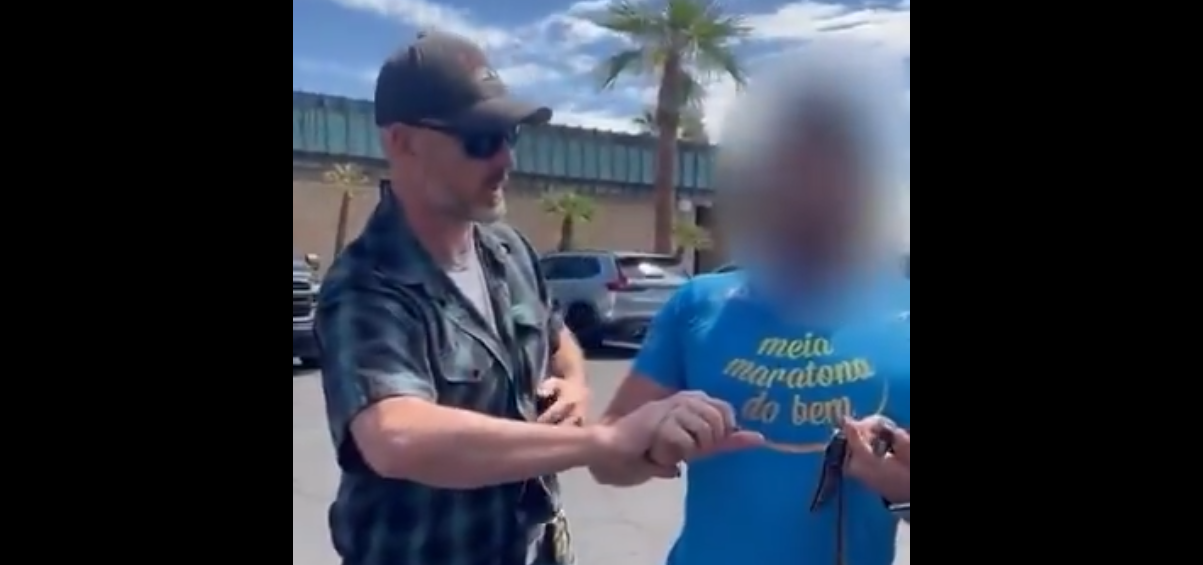 a man in a blue shirt being detained by a plainclothes cop